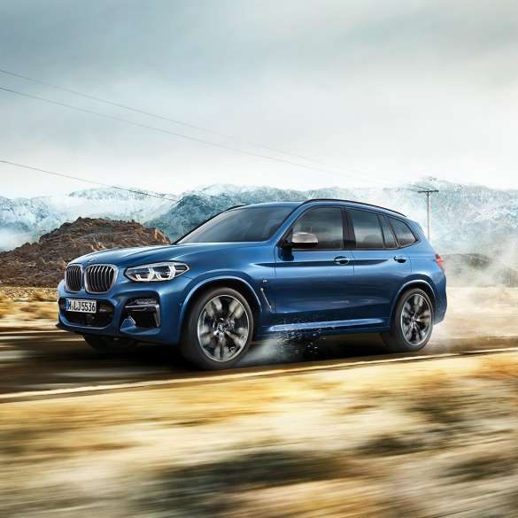 BMW X3 M40i, plan moyen de la jante et de l’aile devant un paysage montagneux BMW X3 M40i, plan moyen de la jante et de l’aile devant un paysage montagneux