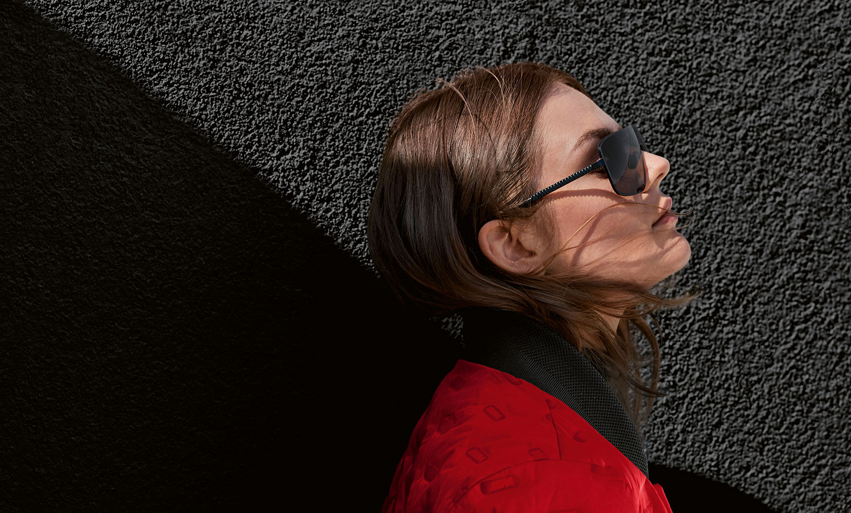 Veste BMW M pour femme et lunettes de soleil BMW M. Une jeune femme porte le blouson BMW M pour femme et les lunettes de soleil BMW M.