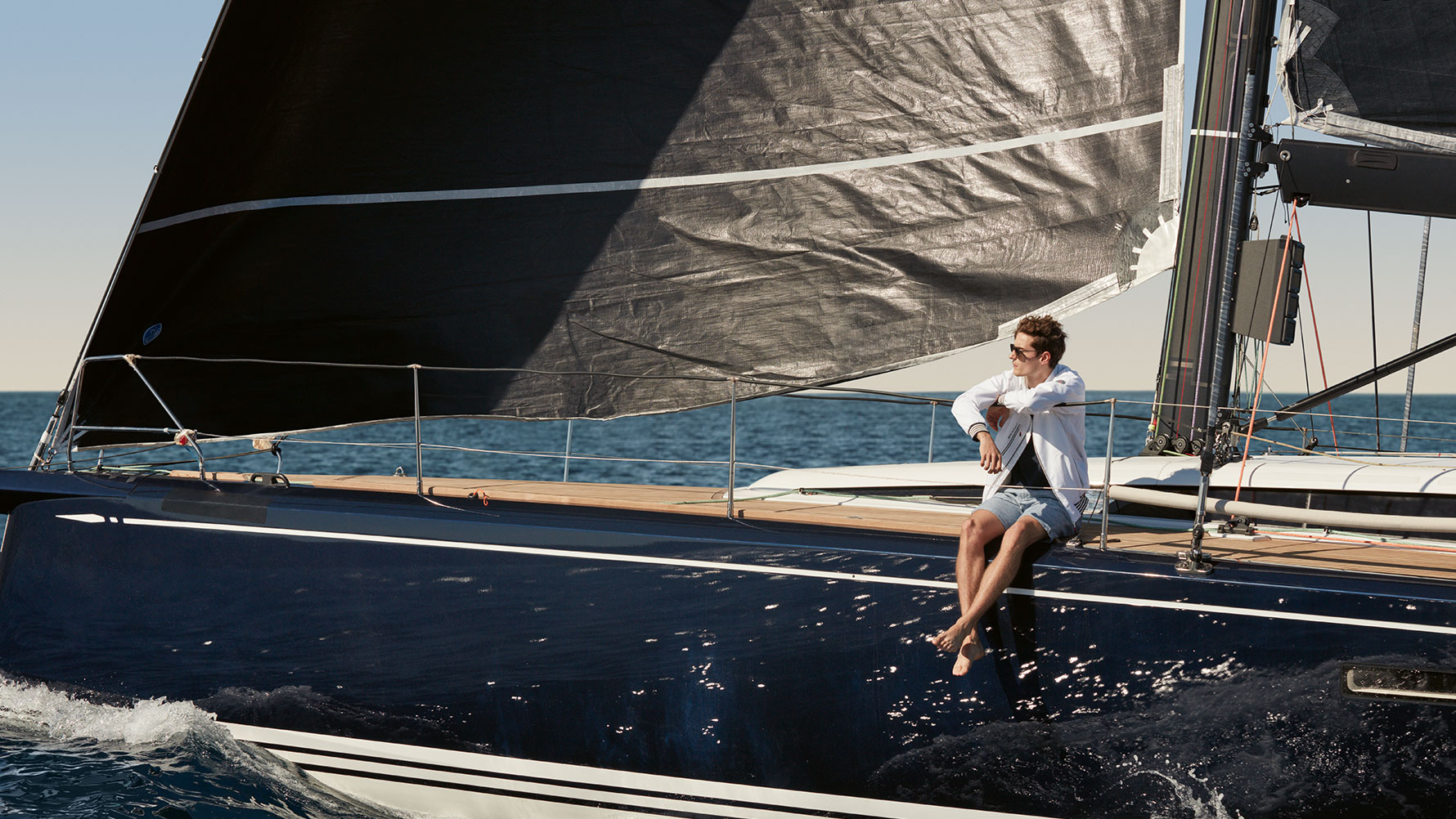 Un homme, assis sur un yacht à voile, porte un blouson pour homme BMW Yachtsport issu de la collection BMW Yachtsport. Un homme, assis sur un yacht à voile, porte un blouson pour homme BMW Yachtsport issu de la collection BMW Yachtsport.