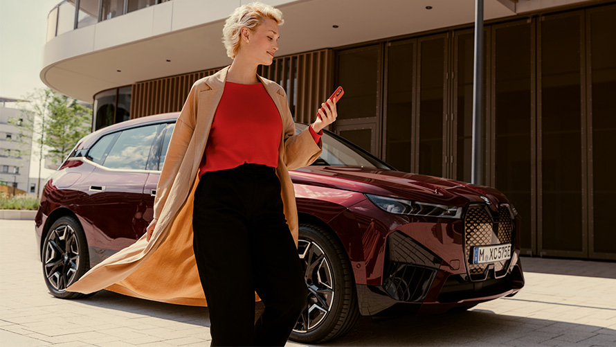 App My BMW, femme avec smartphone devant une BMW Femme avec smartphone devant une BMW